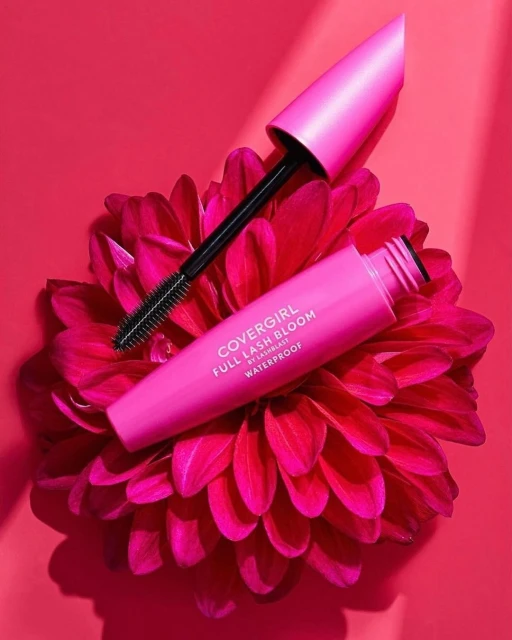 Covergirl Full Lash Bloom waterproof mascara on a pink dahlia against a pink backdrop, cosmetic product shot. Beauty and makeup.