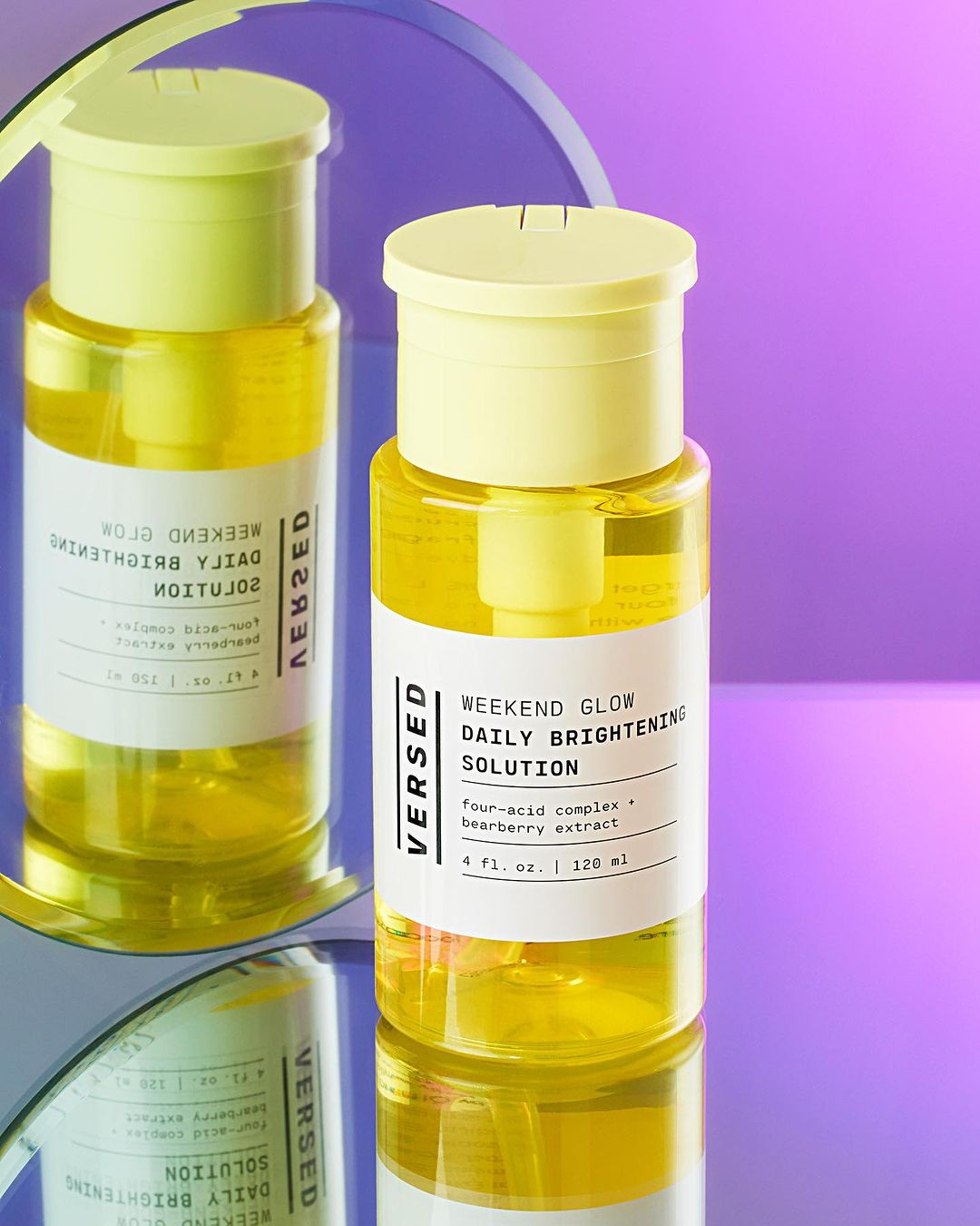 Versed Weekend Glow Daily Brightening Solution in clear bottle with yellow lid and liquid. Beauty product still life against purple background.