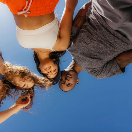 Low-angle shot of three people looking down against a bright blue sky, photographed by Emily Hlavac Green.
