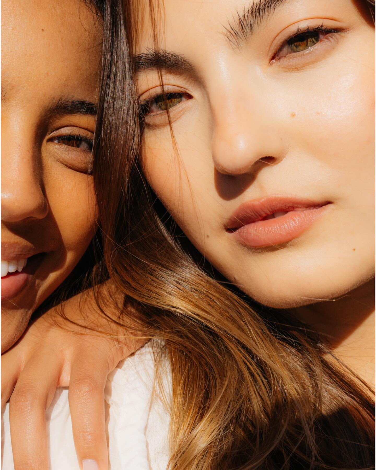 Close-up portrait of two diverse young adult women with radiant skin and natural make-up in soft lighting. Beauty and skincare concept.
