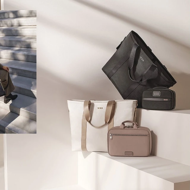 Four Tumi bags in black, white, and beige, are displayed against a white backdrop, with a person on stairs visible in the background.