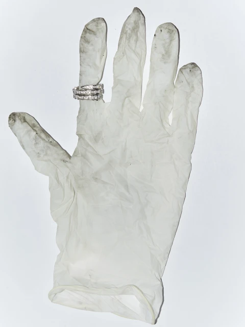 Three diamond rings displayed on the index finger of a dirty, white, latex glove against a plain, white backdrop in a studio shot.