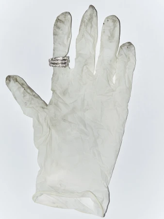 Three diamond rings displayed on the index finger of a dirty, white, latex glove against a plain, white backdrop in a studio shot.