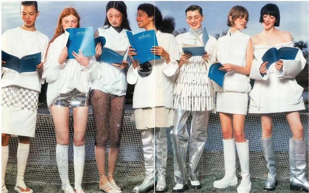 Seven models in white and silver outfits holding Mozart books. The fashion shot features a group standing in a line for editorial purposes.