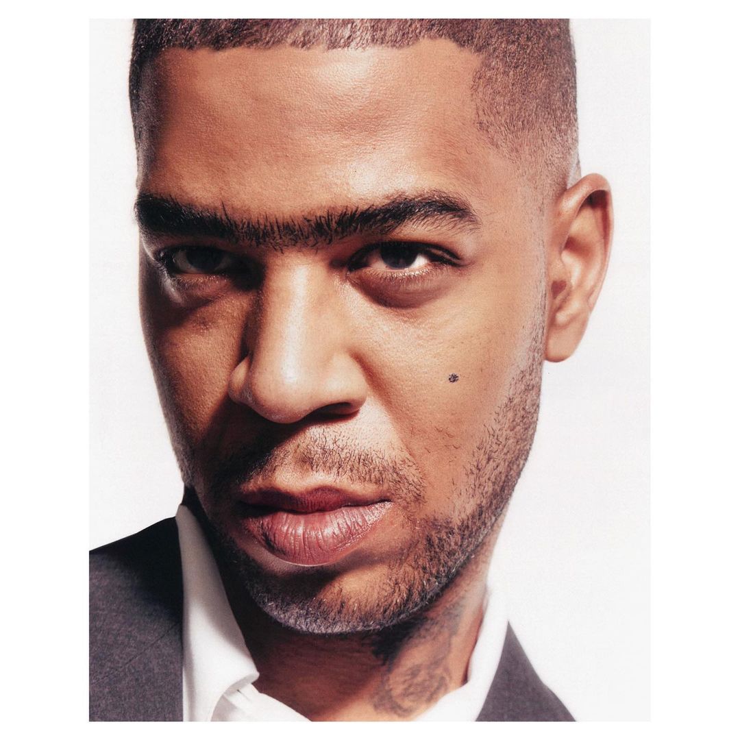 Portrait of a Black man with short hair wearing a white shirt and dark jacket against a plain white background.