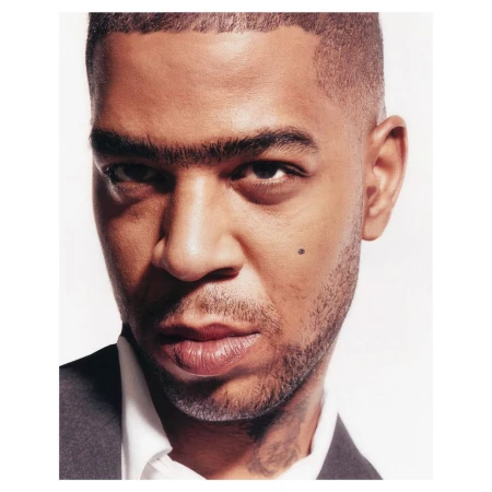 Portrait of a Black man with short hair wearing a white shirt and dark jacket against a plain white background.