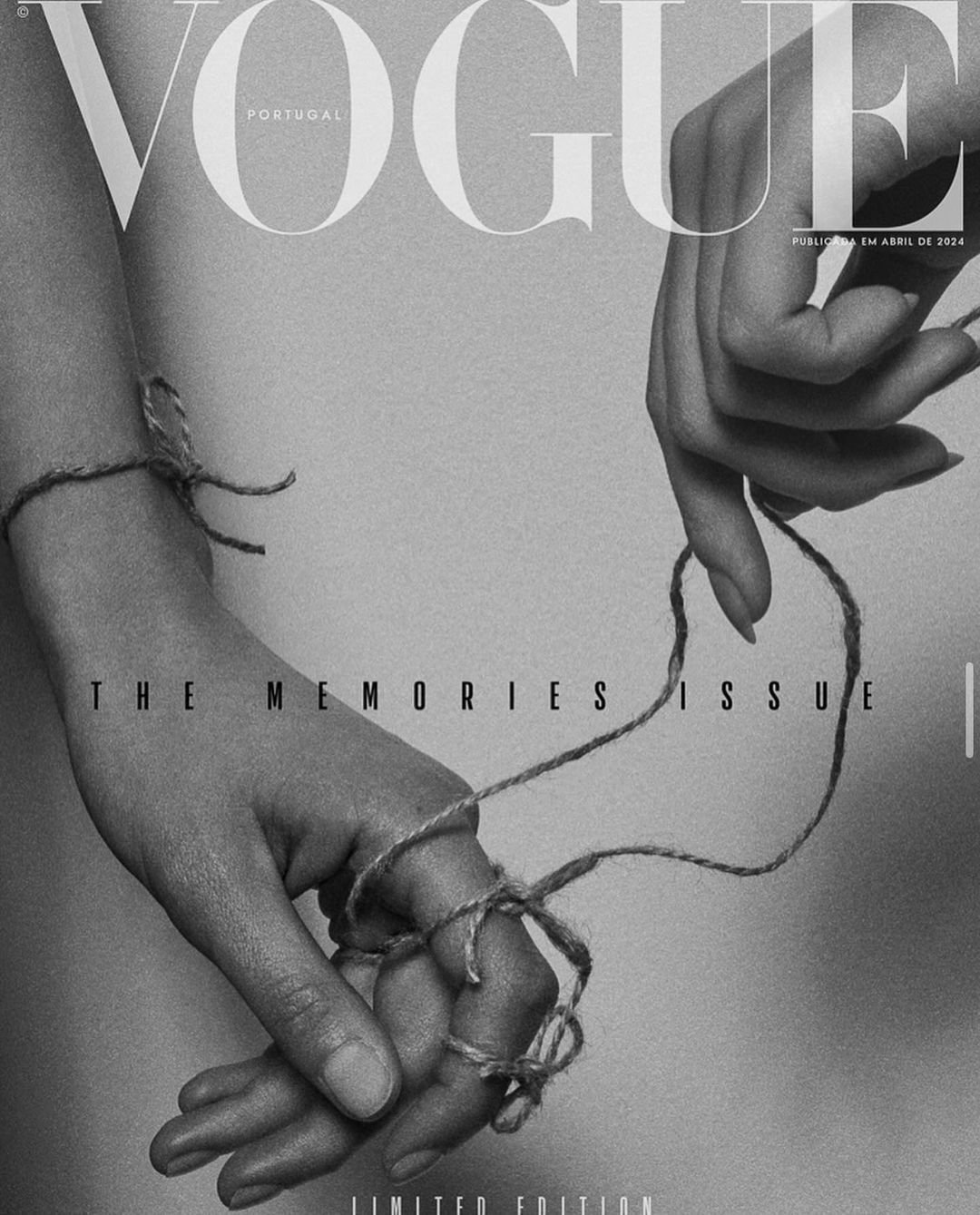 Black and white Vogue magazine cover featuring two hands connected by twine, against a simple background with the magazine's title.