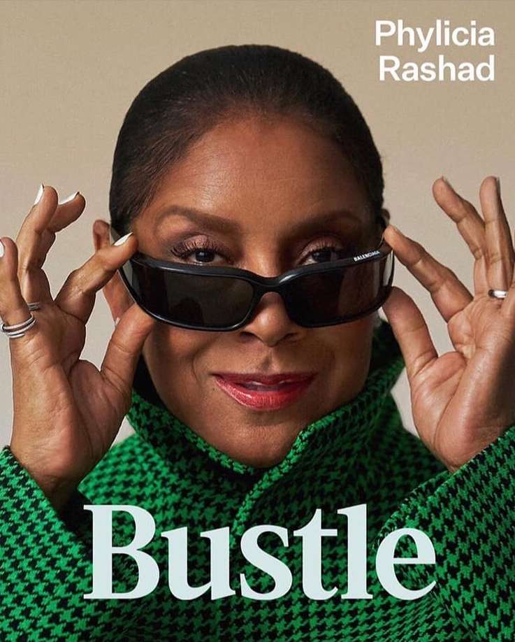 Close-up of Phylicia Rashad wearing sunglasses and a houndstooth coat, smiling at the camera for a magazine cover shoot.