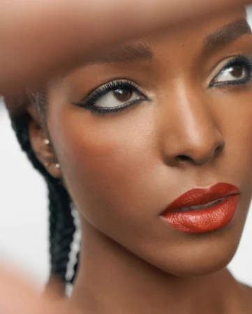 Close-up portrait of a Black woman with winged eyeliner and bold red lipstick photographed by Emily Soto.