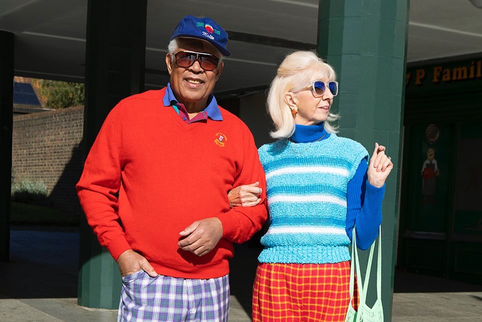 Elderly couple outdoors in vintage clothing. The man wears a red sweater and plaid pants; the woman has a striped top and plaid skirt.