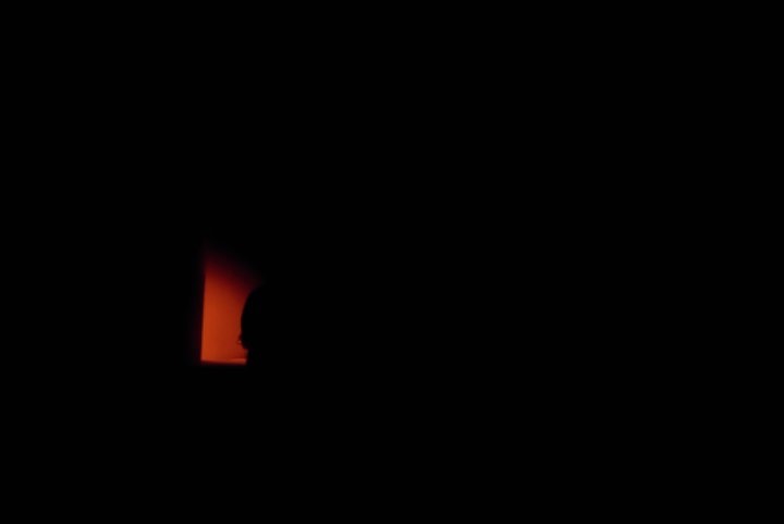 Silhouette of a person in a dimly lit space with a faint orange glow, capturing a sense of mystery and introspection.