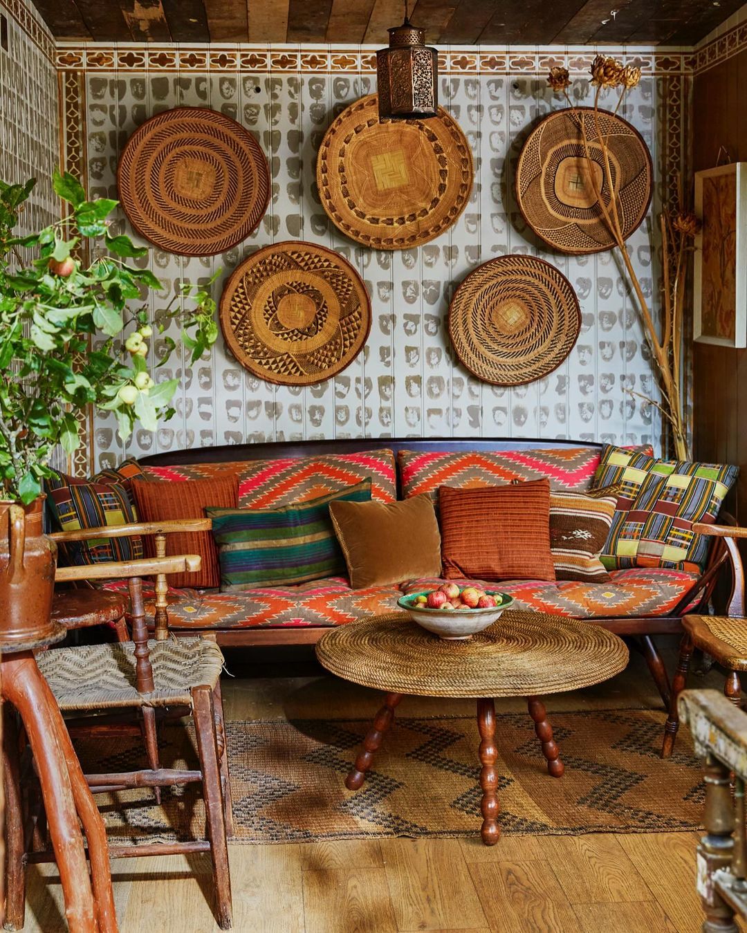 Eclectic living room with patterned sofa, round coffee table, woven wall decor, and rustic wood accents creating a cozy, bohemian interior.
