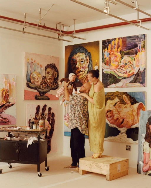 Artist couple in their studio with their baby in front of several large modern art paintings in neutral and earthy colors.