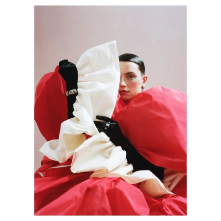 A woman wearing a voluminous red and white garment holding black gloves, photographed by Emma Dalzell-khan in London