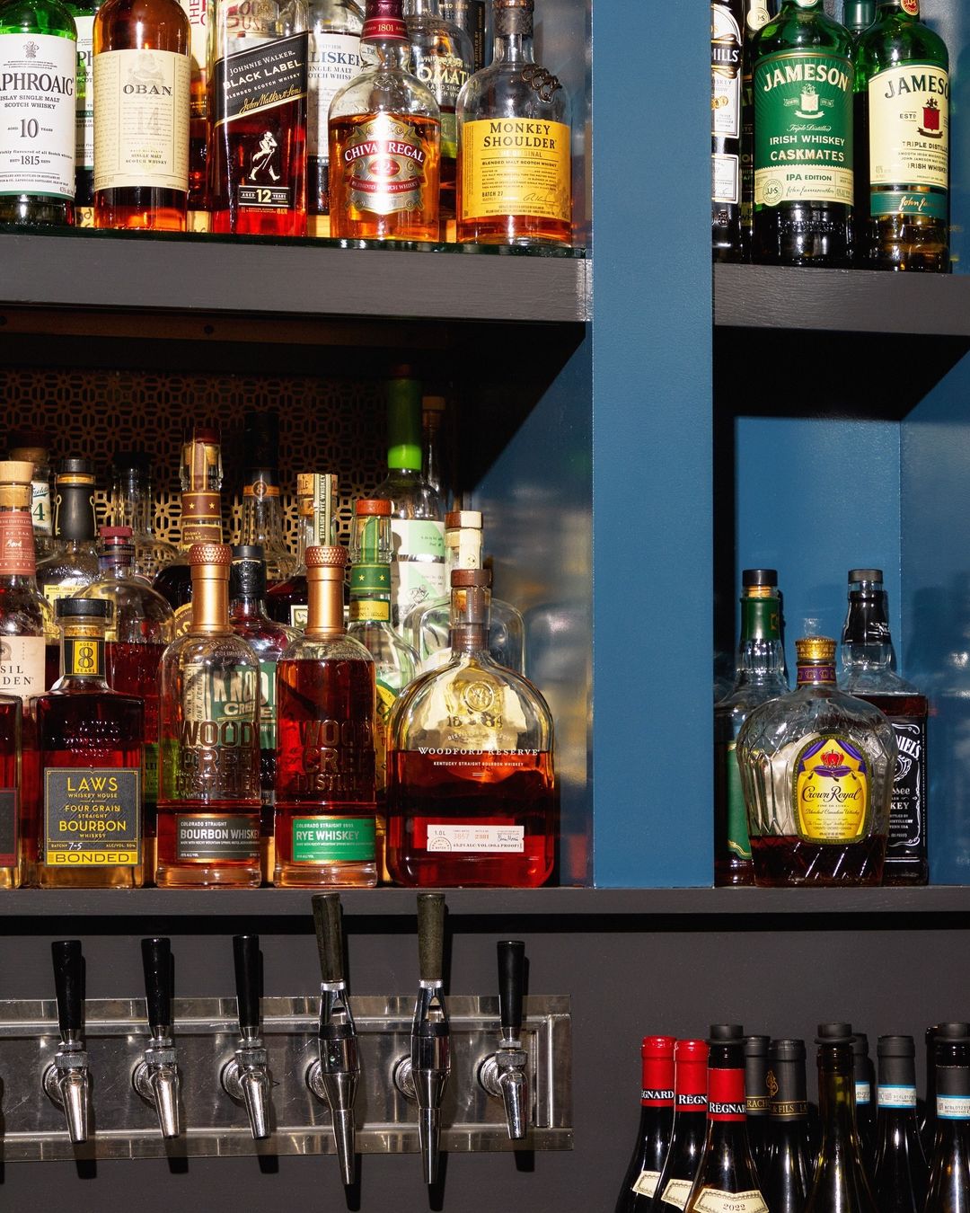 A liquor bar with shelves stocked with various bottles of whiskey, scotch, and spirits in a dimly lit ambiance.