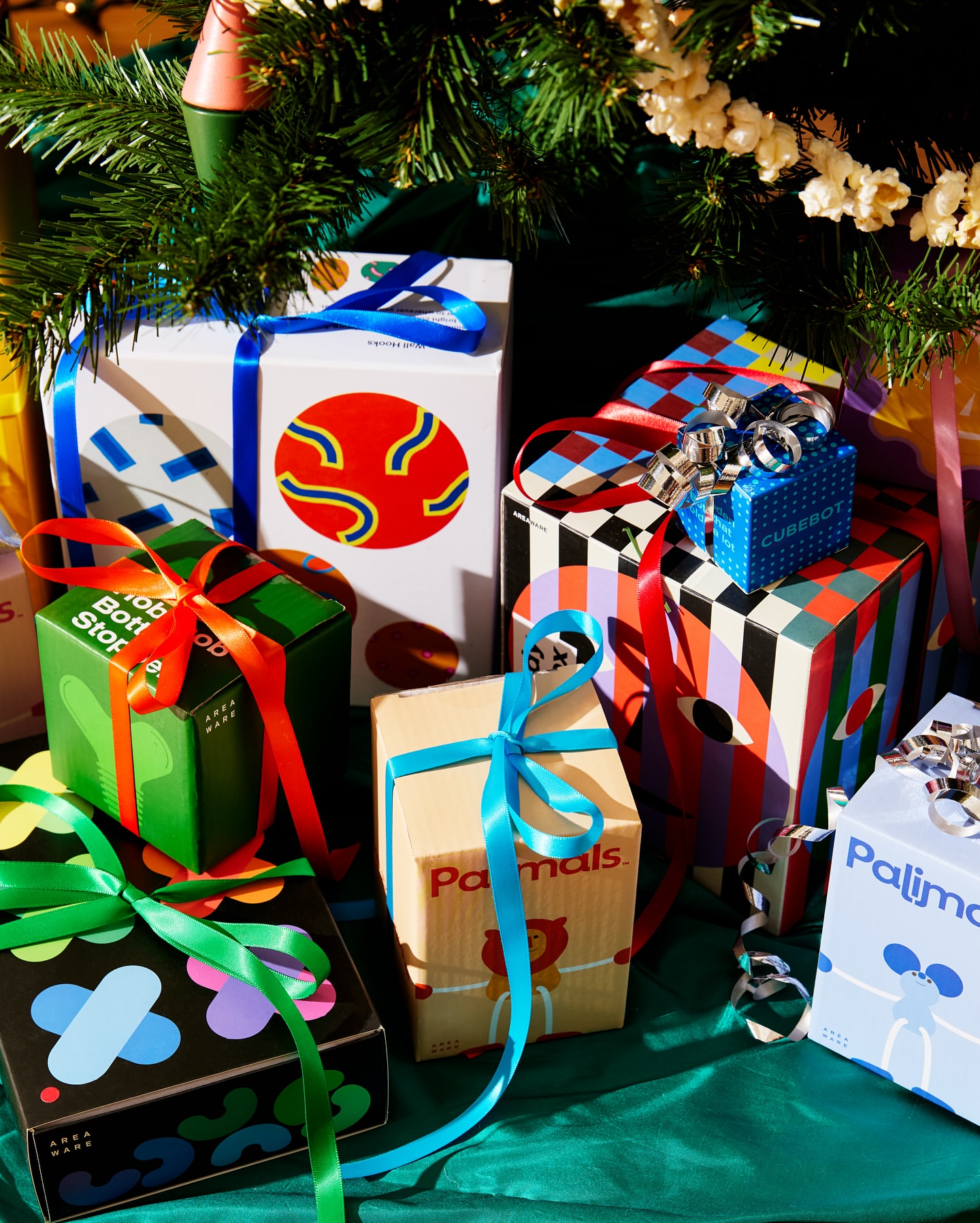 Festive Christmas presents with colorful graphic designs, ribbons, and seasonal decor under a tree, creating a cheerful holiday scene.