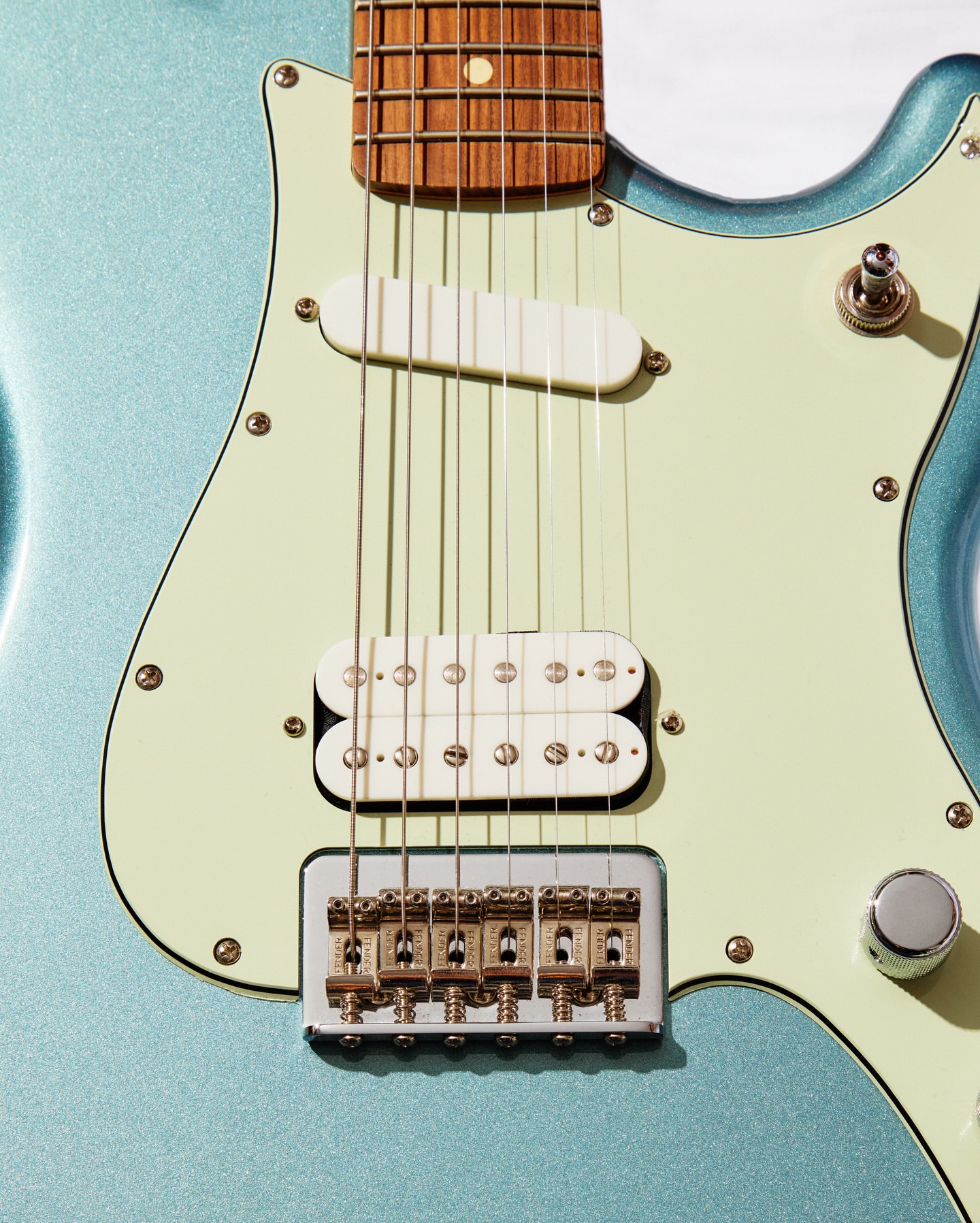 Close-up of a light blue electric guitar with white pick-ups, strings, and gold hardware on a white background. Musical instrument.