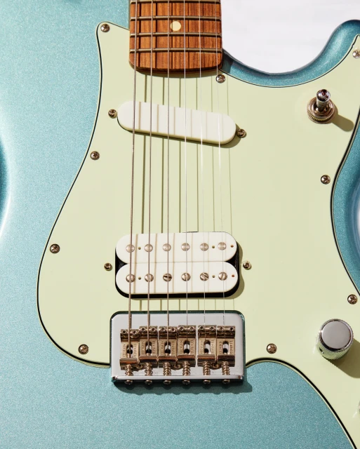 Close-up of a light blue electric guitar with white pick-ups, strings, and gold hardware on a white background. Musical instrument.