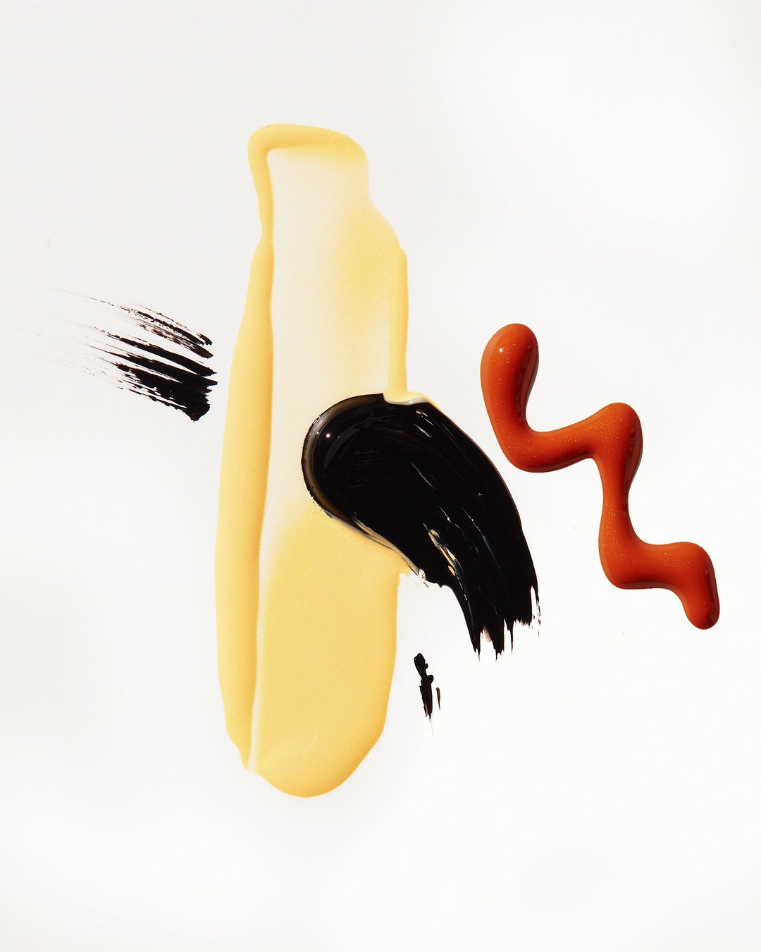 Abstract beauty product shots featuring splashes of yellow, black, and red makeup on a clean white background, studio lighting.