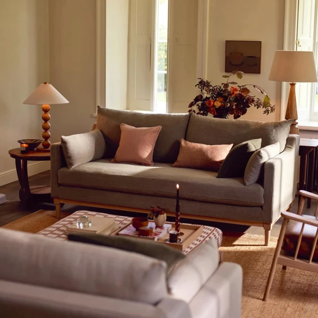Interior shot showcases a green sofa with cushions, wooden accents, and a floral centerpiece, creating a cozy and inviting living space.