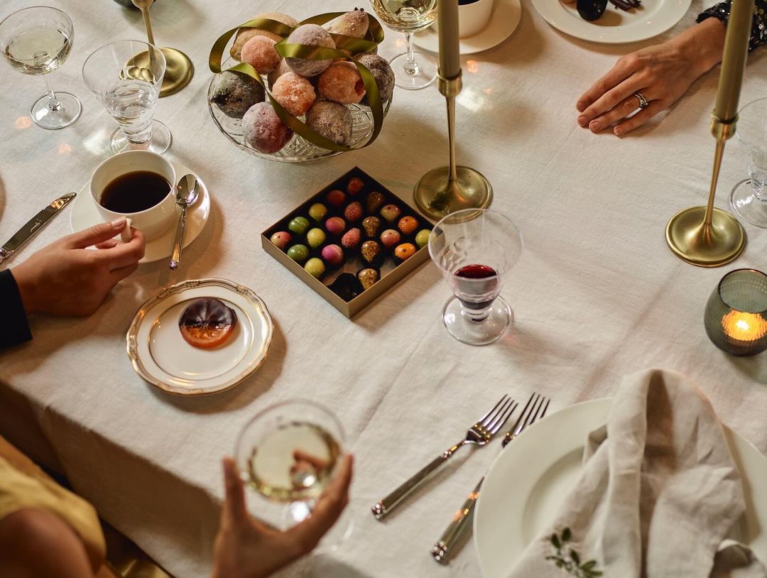 Overhead view of a beautifully set table with treats, drinks, cutlery, candles, and a napkin, creating an inviting and festive atmosphere.