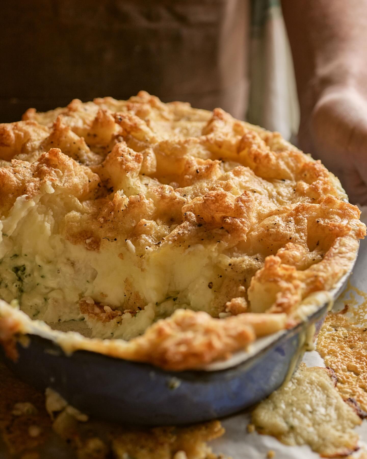 Close-up shot of a freshly baked pie in a blue ceramic dish, showcasing its golden-brown crust and creamy filling, indoors.
