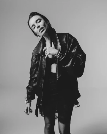 Monochrome portrait of a woman wearing an oversized leather jacket against a light background