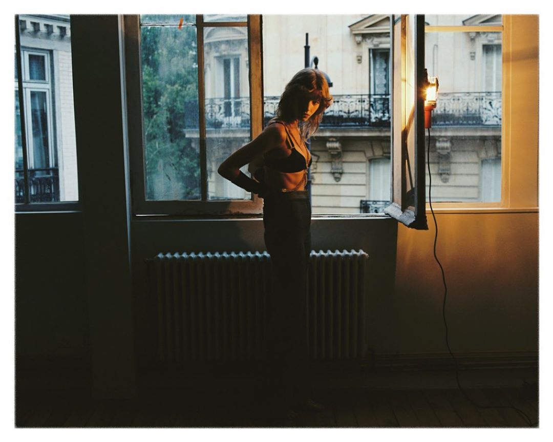 Woman in dark underwear standing by an open window in a Paris interior photographed by Emma Picq