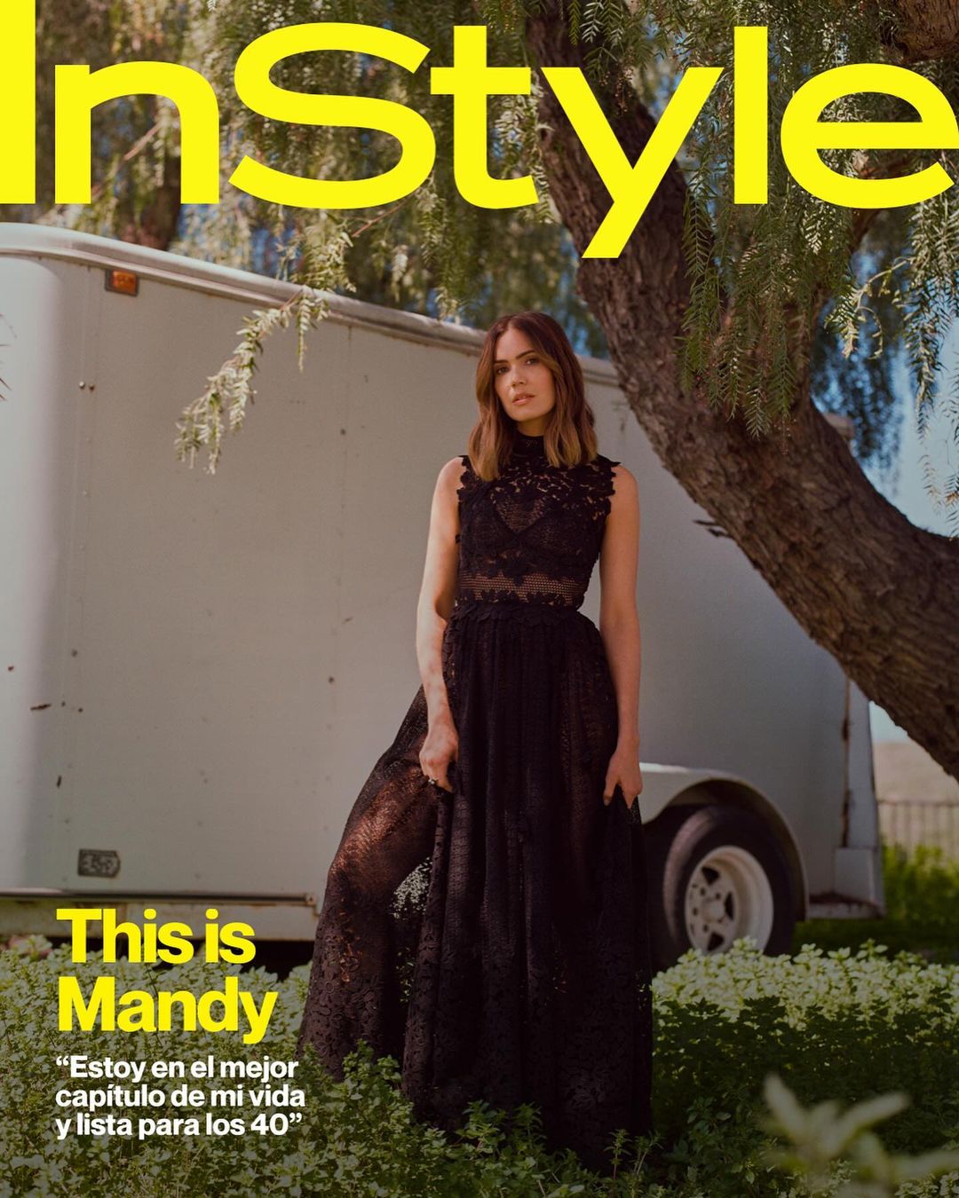 Magazine cover featuring Mandy Moore in a black lace dress, posing outdoors with a trailer and foliage in the background.