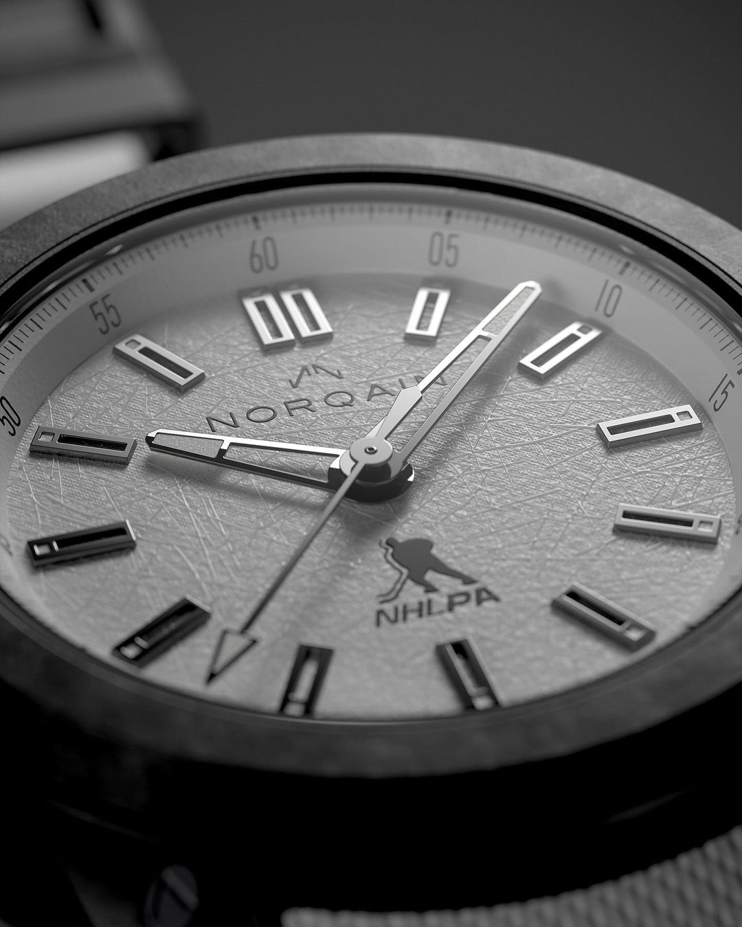 Close-up of a black and white Norqain wristwatch with silver hands and hour markers. The watch has the NHLPA logo printed on the face.