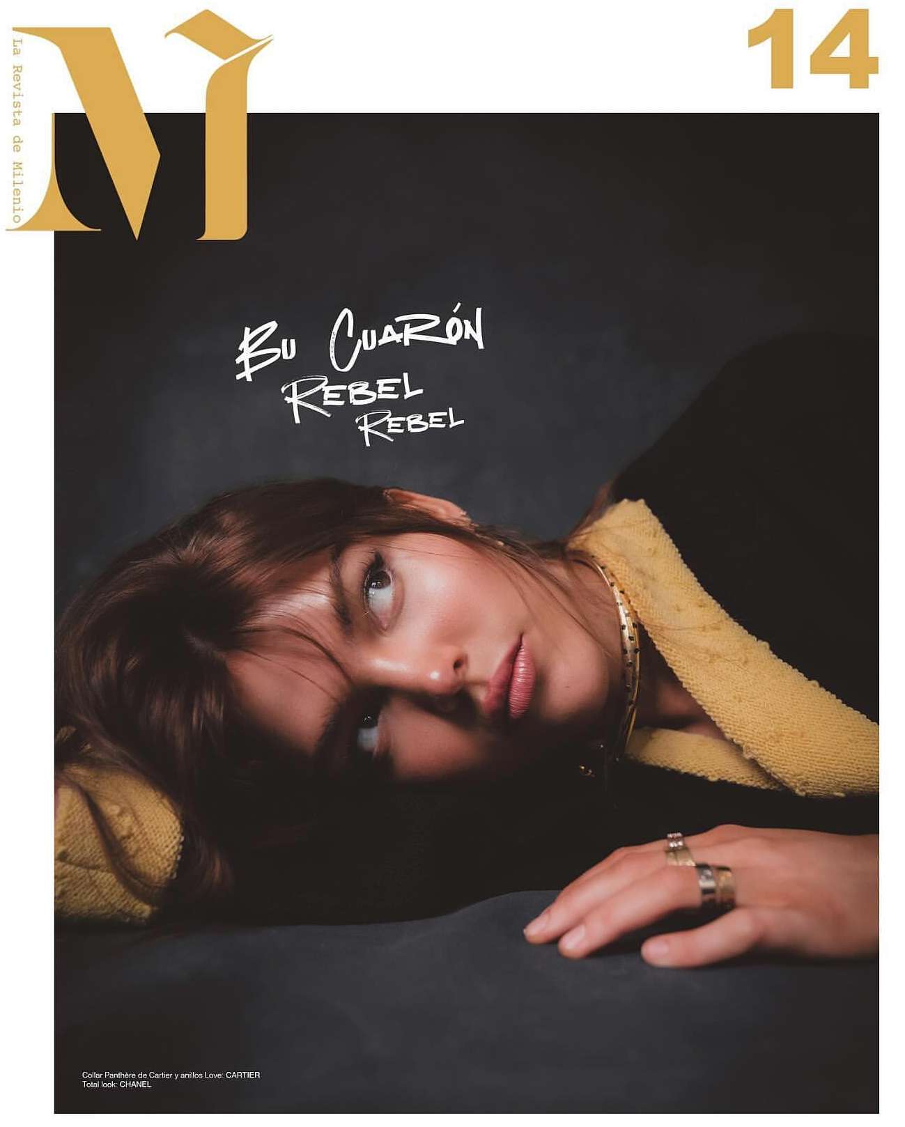 Magazine cover featuring a woman with light brown hair lying down, wearing rings and a gold chain, against a dark gray background.