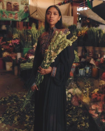 Portrait of a woman holding a large bouquet of green flowers inside a flower market photographed by Enrique Leyva