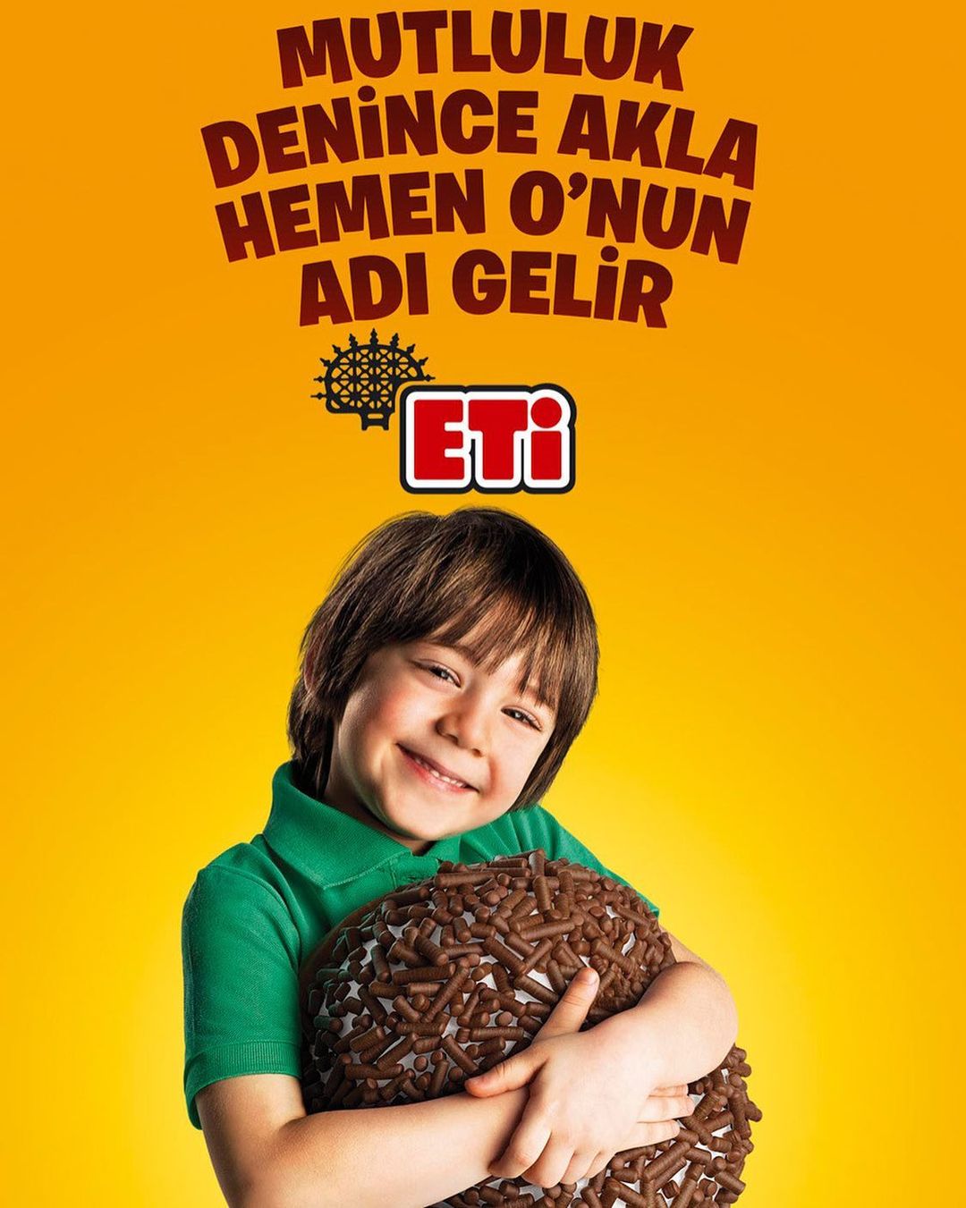 A smiling child hugs a chocolate-covered ball in a studio shot with a vibrant yellow backdrop and Turkish text overhead promoting Eti brand.
