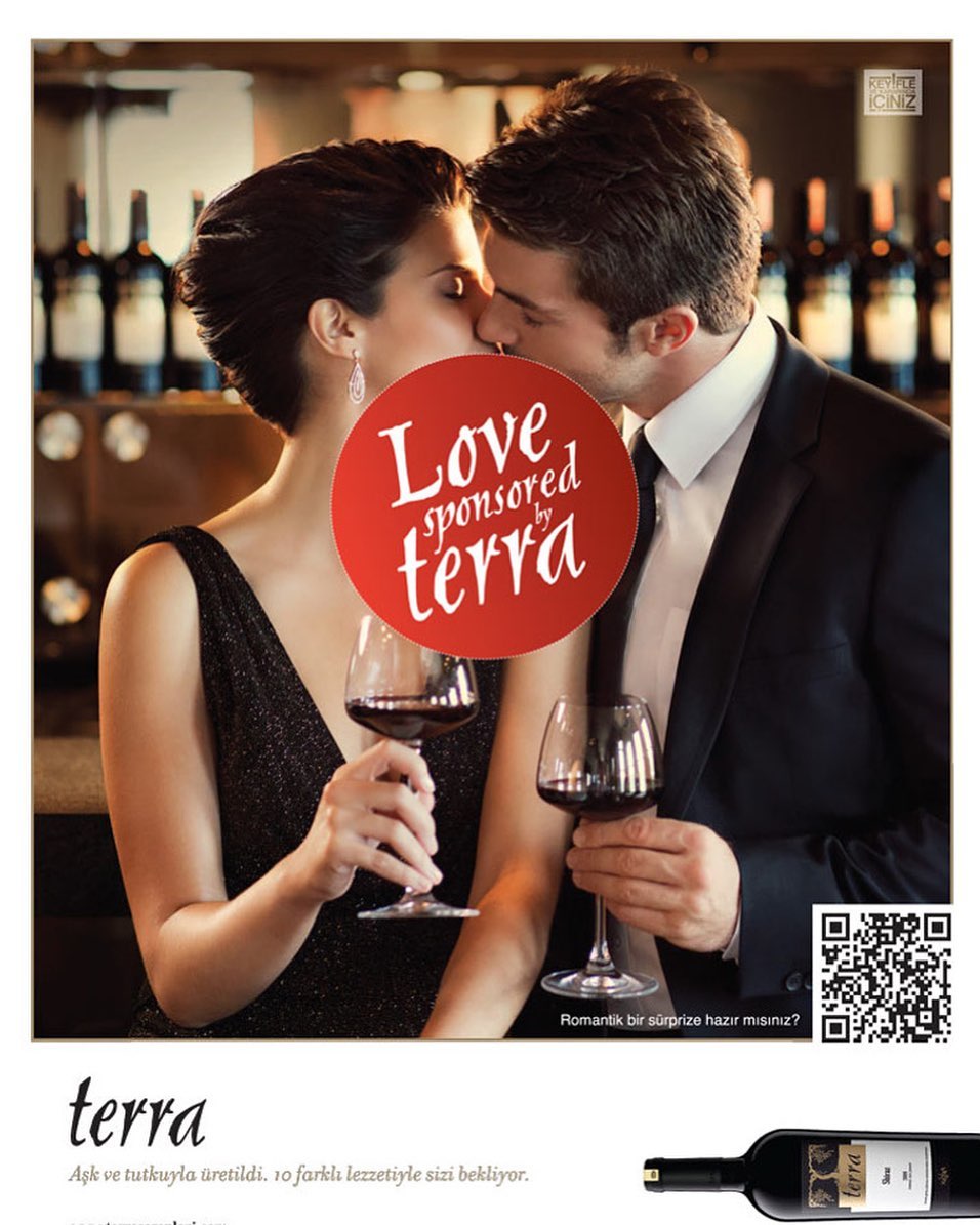 A couple kisses with red wine in foreground, promoting 'Terra' wine with a QR code. Wine bottles are visible in the background.