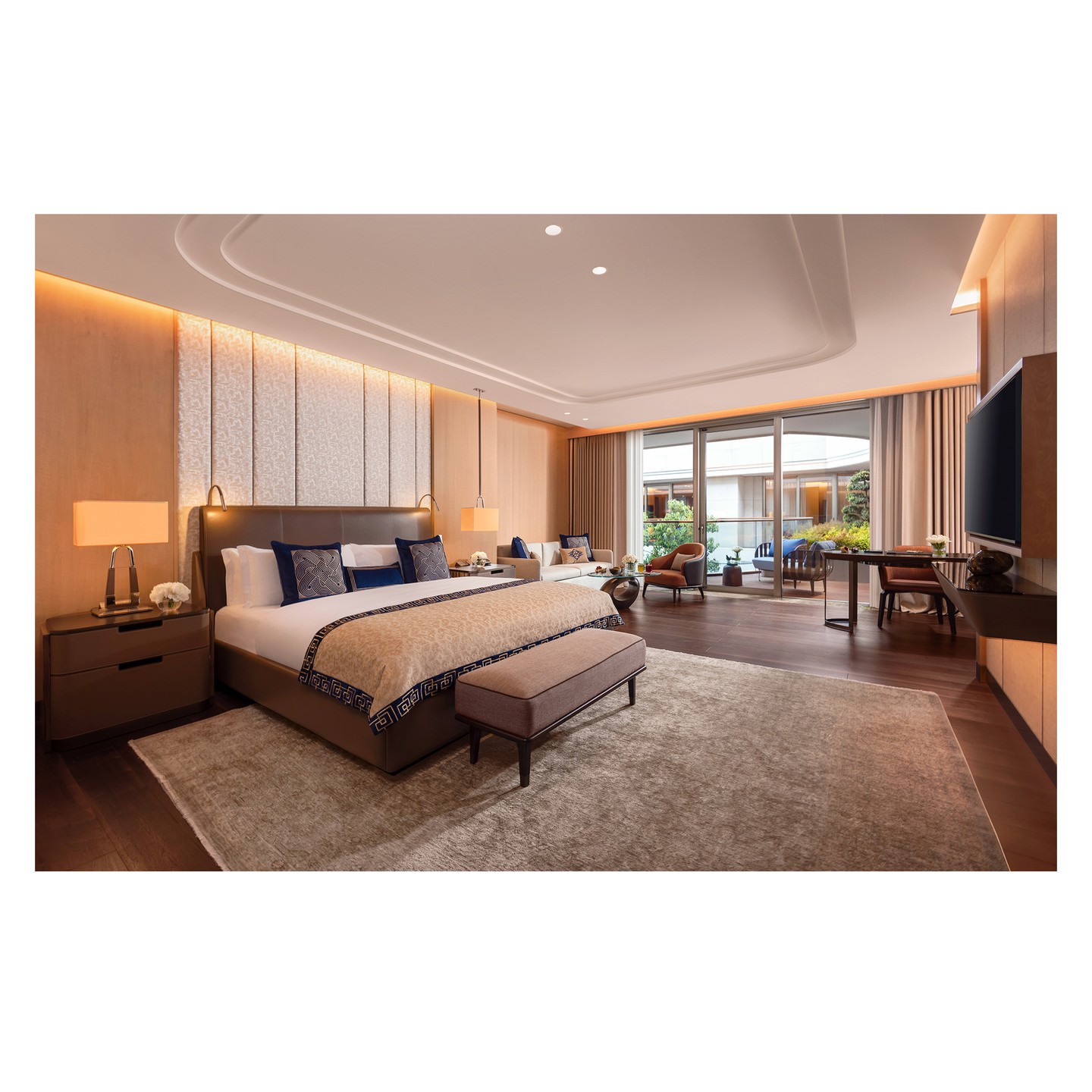 Luxurious bedroom with king-size bed, upholstered headboard, bench, carpet, and view to outdoor patio with lounge chairs.