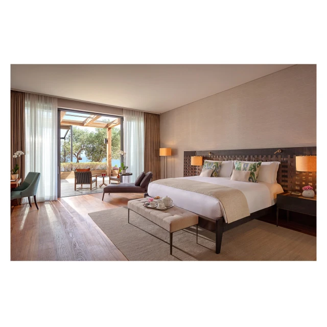 Bedroom interior with a large bed, neutral color scheme, and an outdoor terrace with seating, offering a bright and airy atmosphere.