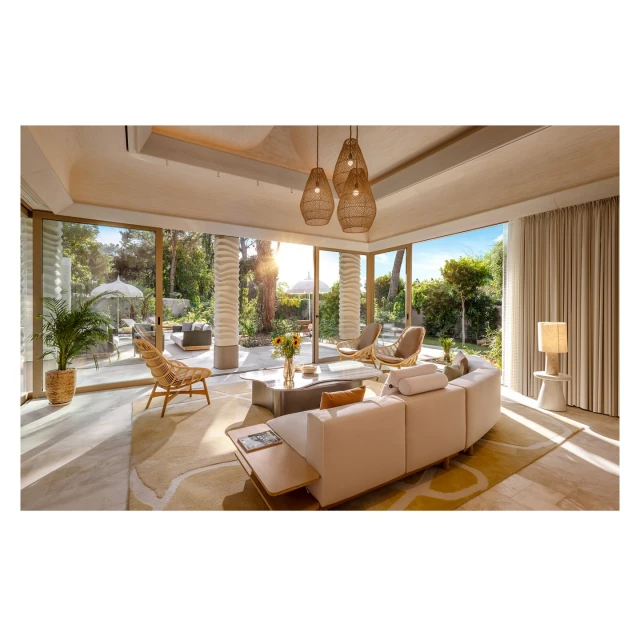 Bright, modern living room interior with a curved sofa, natural light, and outdoor views of a garden and patio space in a home.