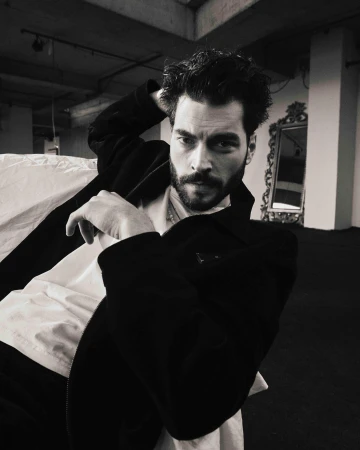 Portrait of a man in a dark jacket and white t-shirt with his hand behind his head, photographed by Erdi Dogan in Istanbul.