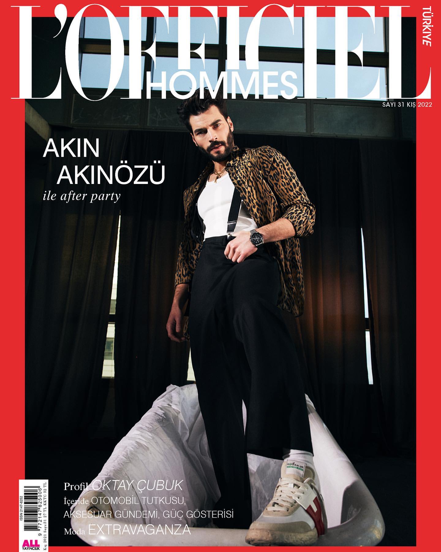 Magazine cover featuring Akin Akinozu wearing a leopard print jacket and black trousers, posing on white material indoors.