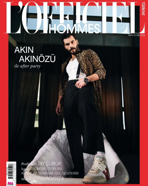 Magazine cover featuring Akin Akinozu wearing a leopard print jacket and black trousers, posing on white material indoors.