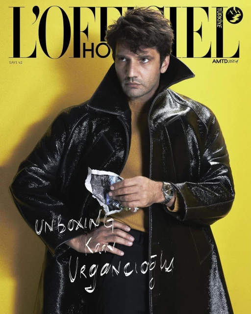 Magazine cover featuring a male model in a black patent leather trench coat and yellow turtleneck against a yellow background.