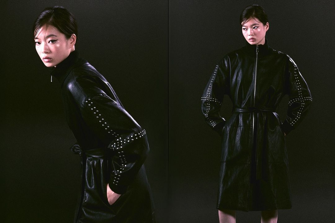 Studio shot of a woman in a black studded leather dress, standing against a dark backdrop. Fashion photography for Visie creative directory.