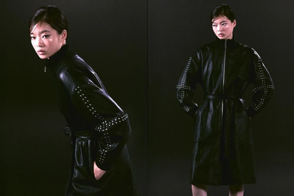 Studio shot of a woman in a black studded leather dress, standing against a dark backdrop. Fashion photography for Visie creative directory.