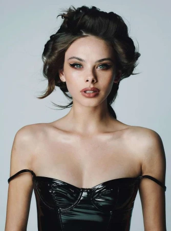 Portrait of a beautiful woman with dark hair styled in curlers, wearing a black shiny strapless top against a neutral background.