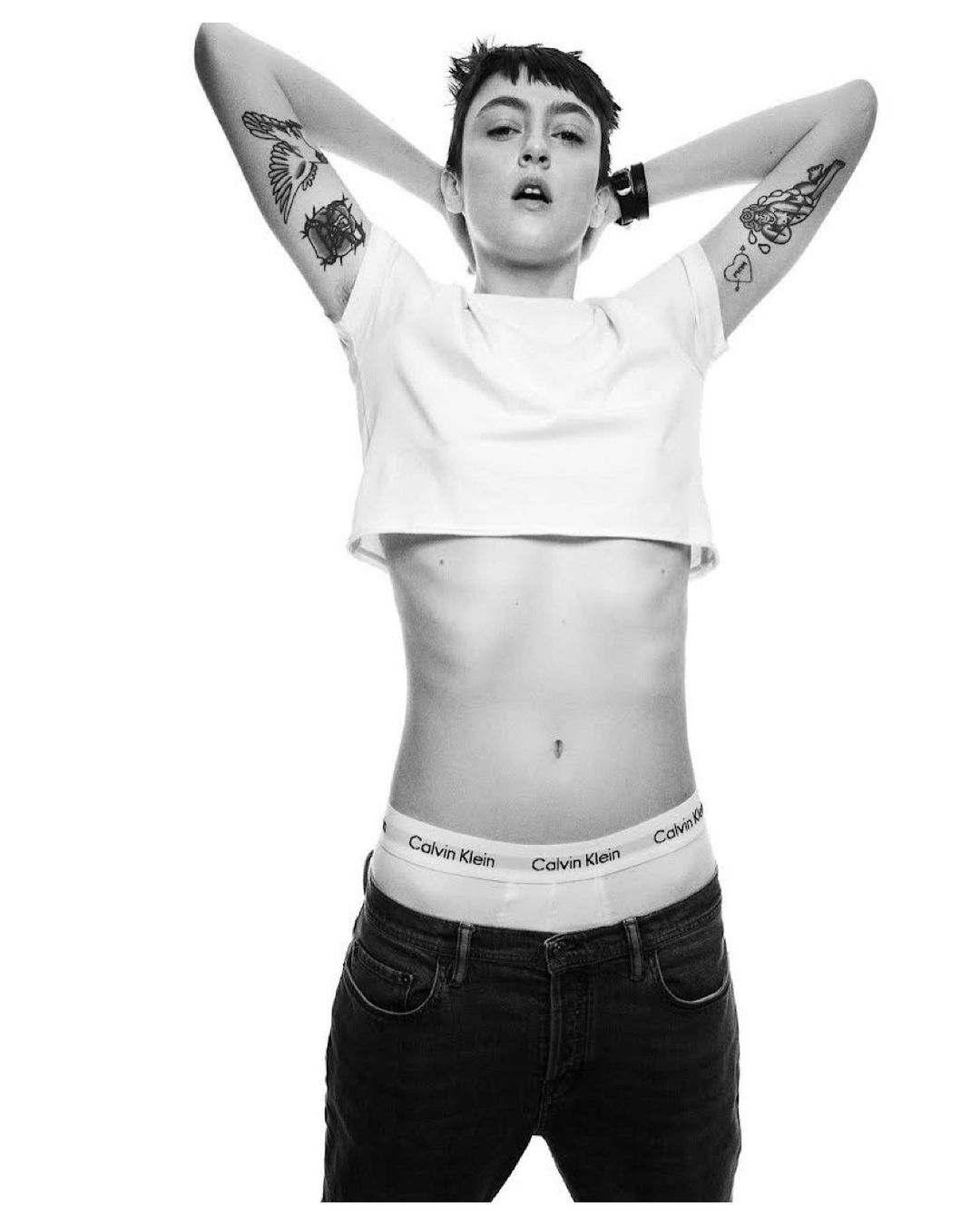 Model with short dark hair and arm tattoos wearing a white crop top and branded underwear by Erez Sabag in Milan
