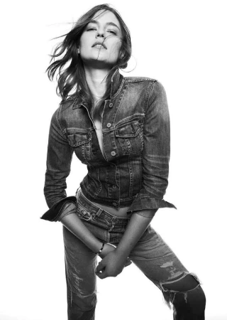Monochrome fashion portrait of a female model wearing a denim jacket and jeans against a white background by Erez Sabag
