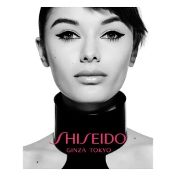 Close-up portrait of a woman wearing winged eyeliner and a rigid black collar with Shiseido Ginza Tokyo branding.