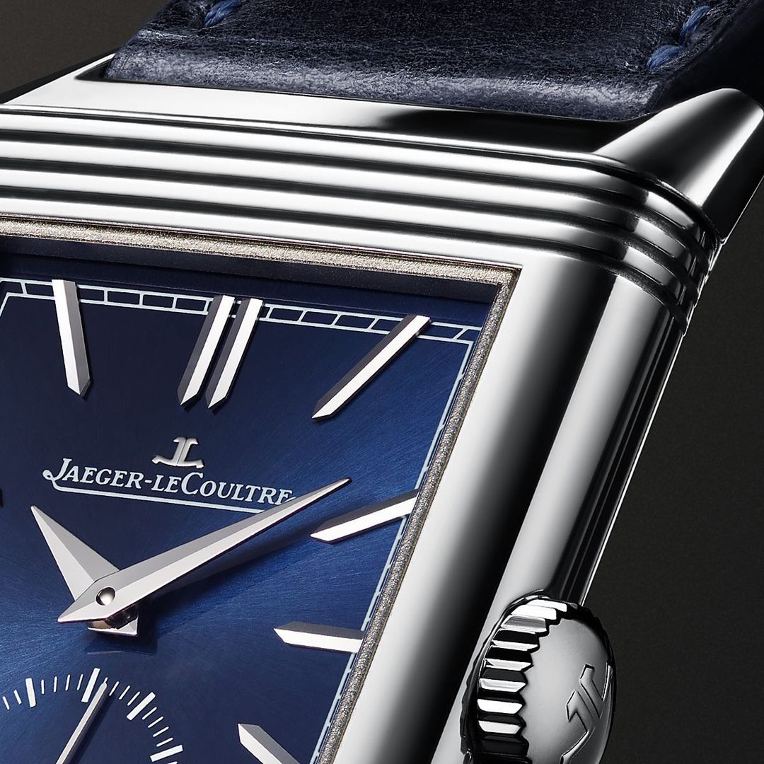 Close-up of a Jaeger-LeCoultre wristwatch featuring a blue face, silver hands and markers, a stainless steel case, and a dark blue leather strap.