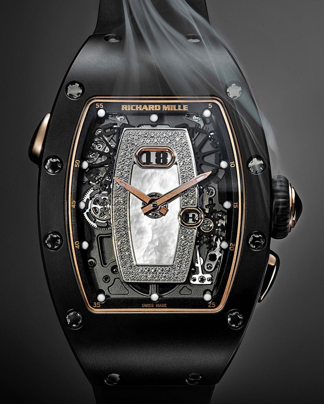Luxury black and rose gold Richard Mille wristwatch featuring an intricate diamond and pearl face, set against a dark gray background with wisps of smoke.