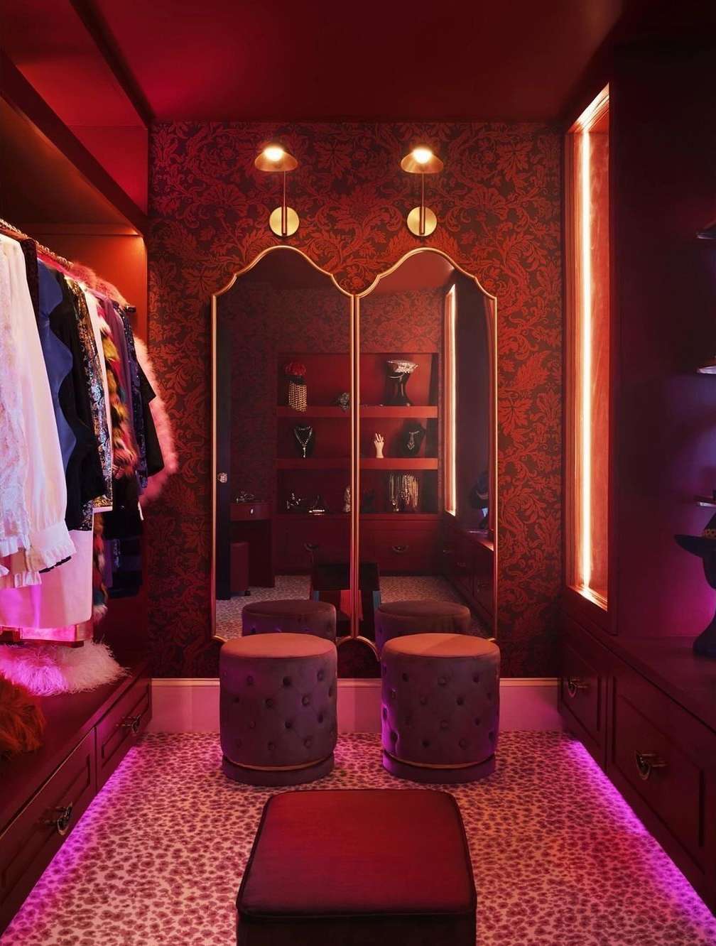 Elegant walk-in closet interior with patterned wallpaper, closet organization system, animal print carpet, and decorative stools.